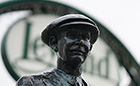 A bronze statue of a man in a flat cap