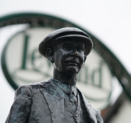 A bronze statue of a man in a flat cap