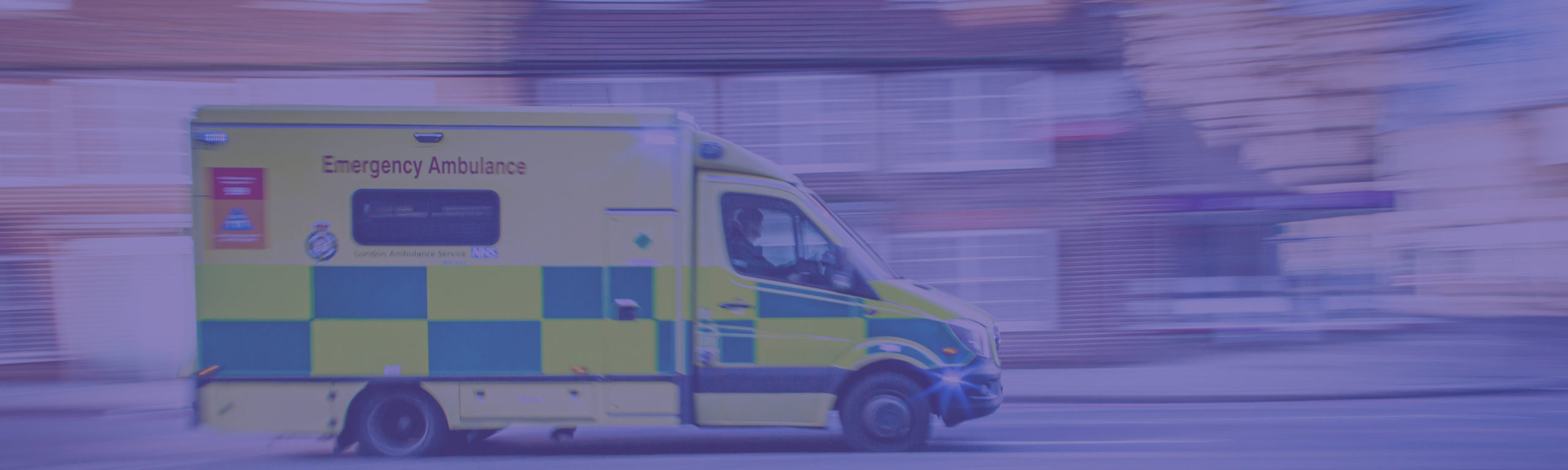 An emergency ambulance speeding along a suburban street