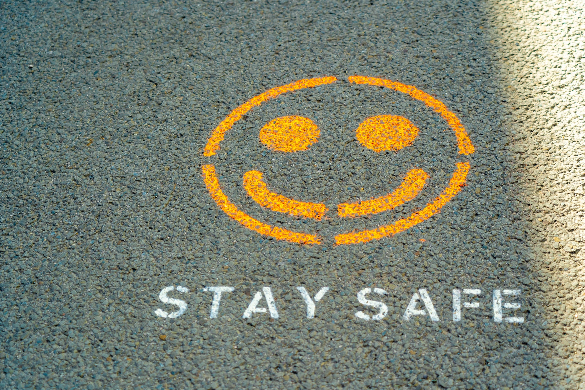 A road marking of a smiley face with the words "Stay safe" underneath it