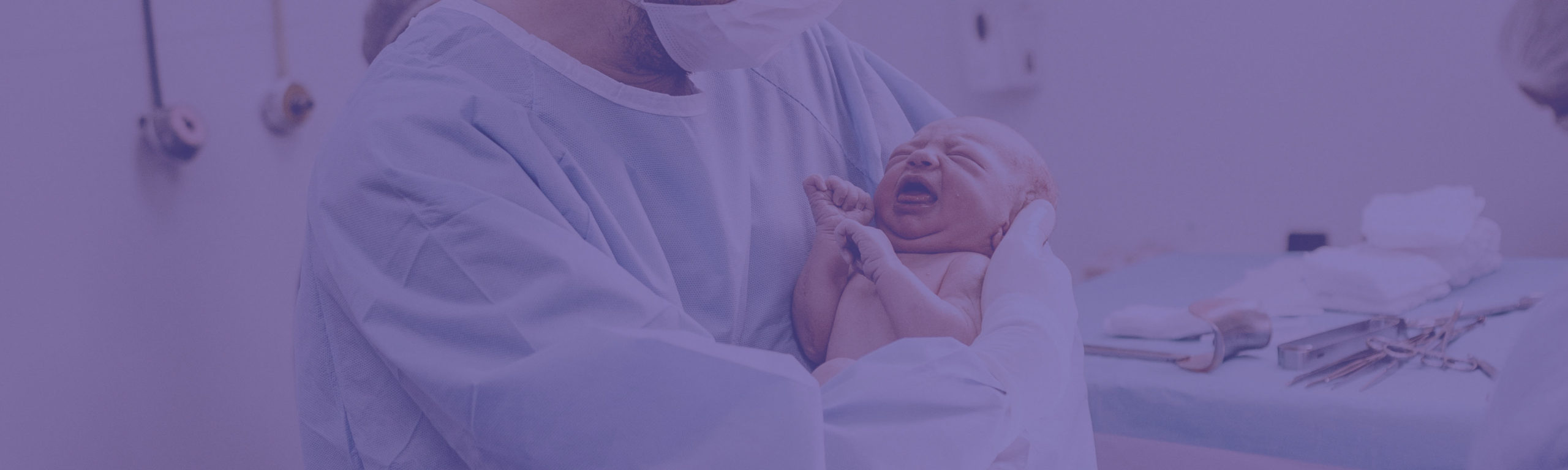 man in hospital scrubs holding a new born baby