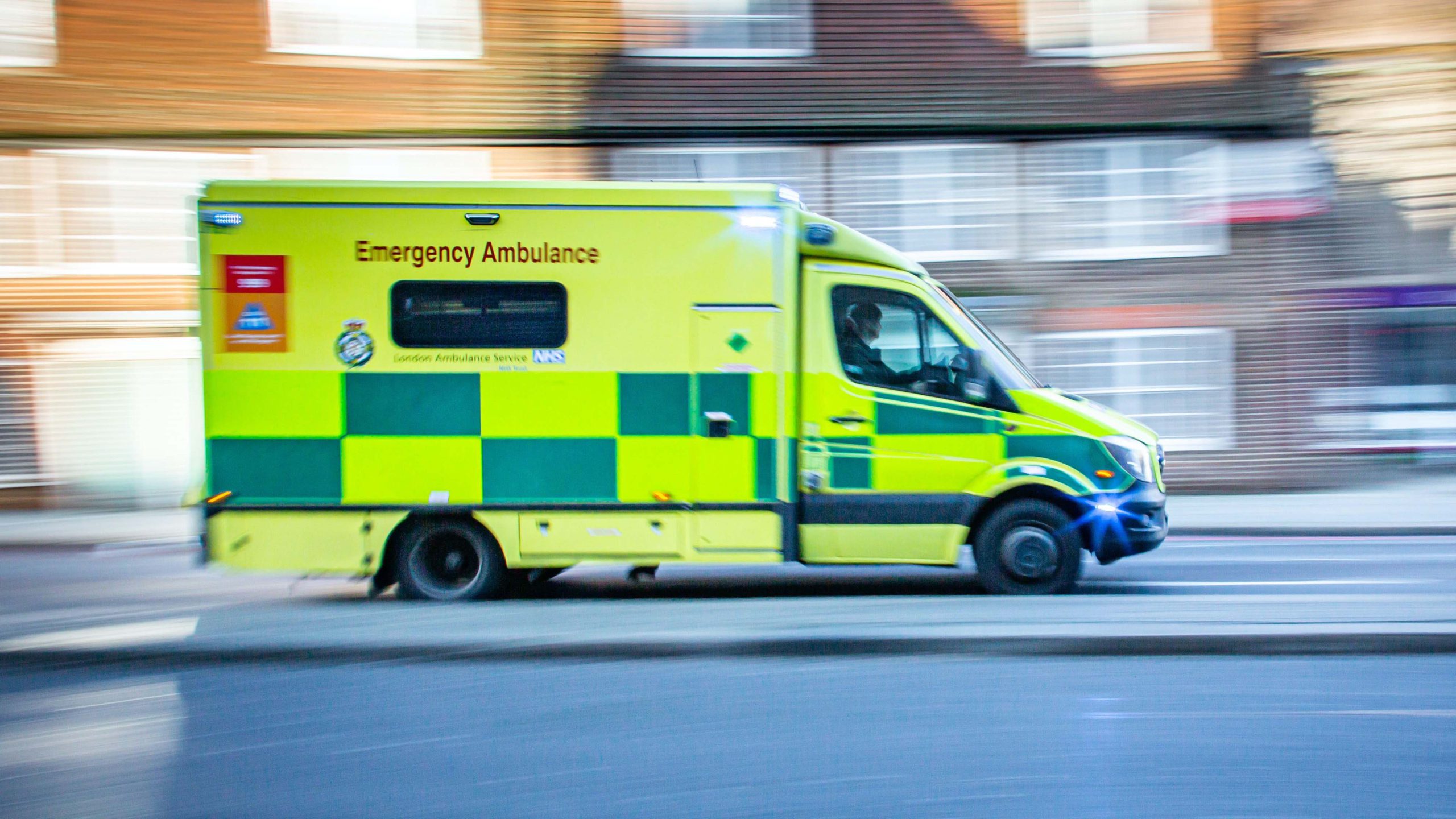 An emergency ambulance speeding along a suburban street