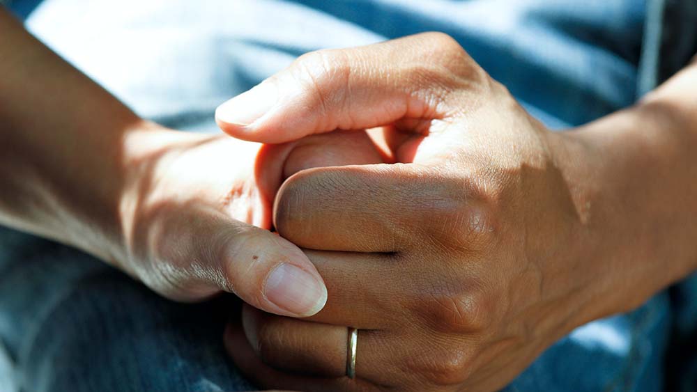 close up of hands holding and one has a wedding ring on