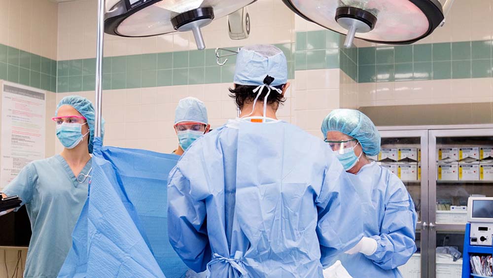 An operating room with four medical professionals in blue scrubs