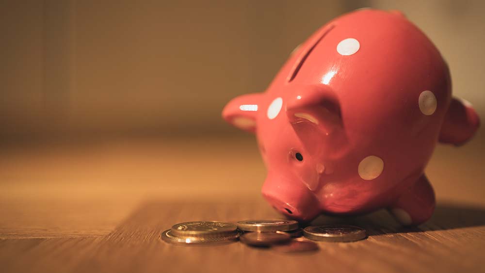 A pink piggy bank tipped forward to count pennies on a table