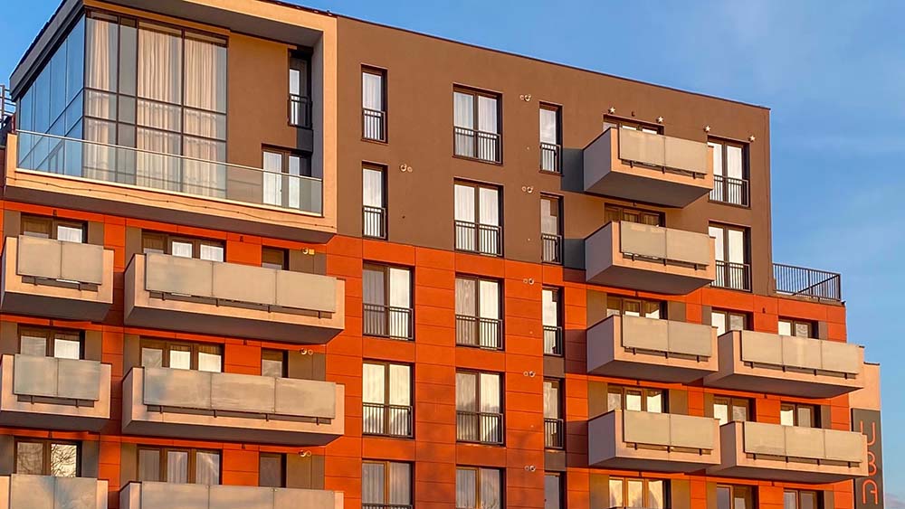 Apartment block of red brick and grey cladding against a blue sky