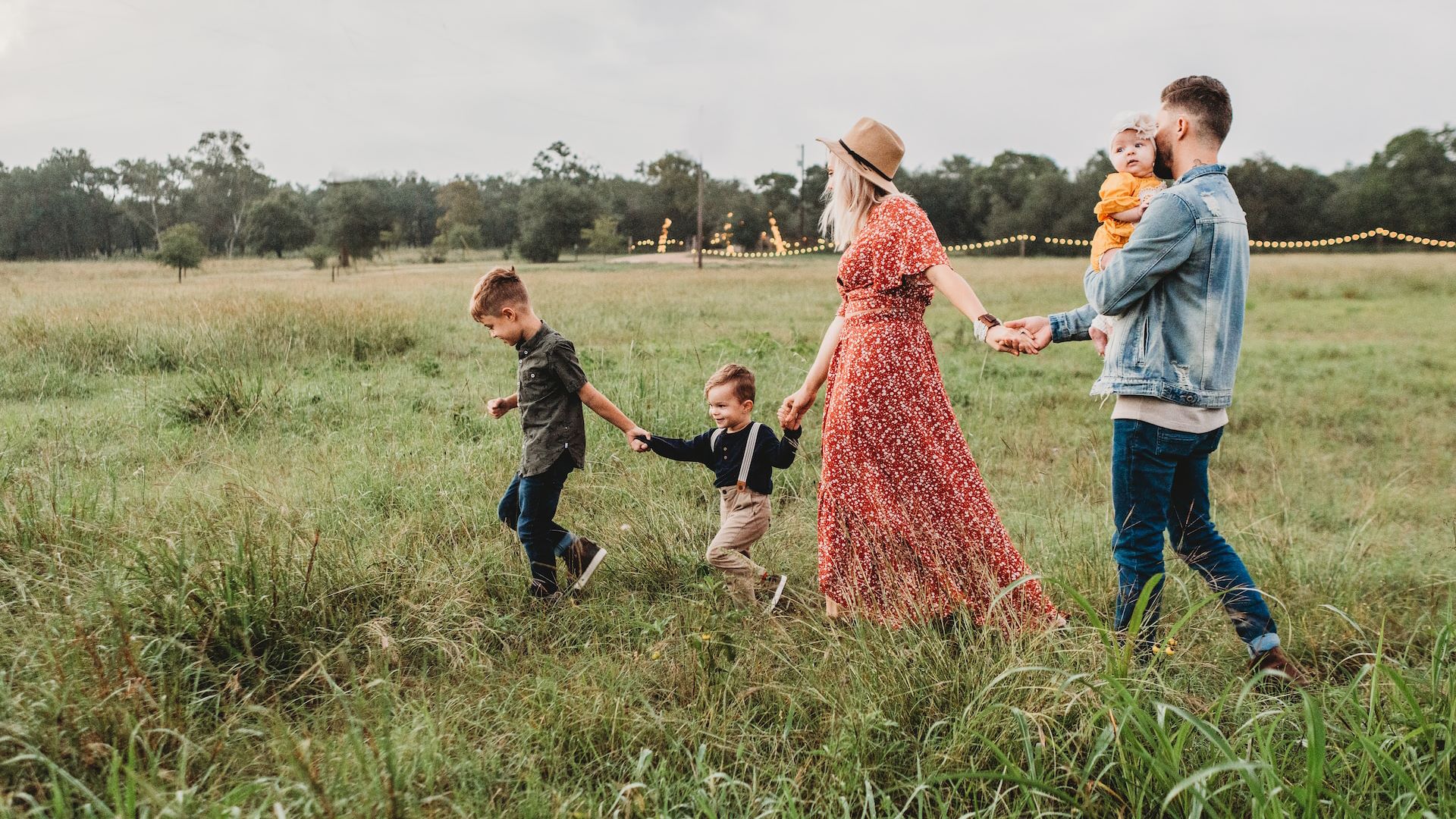 An image of a happy family walking through a field, they have young children.
