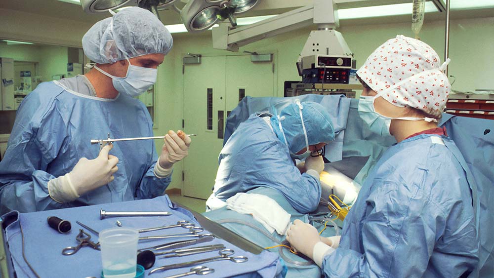 Three surgeons in blue scrubs in the operation room caring for patient