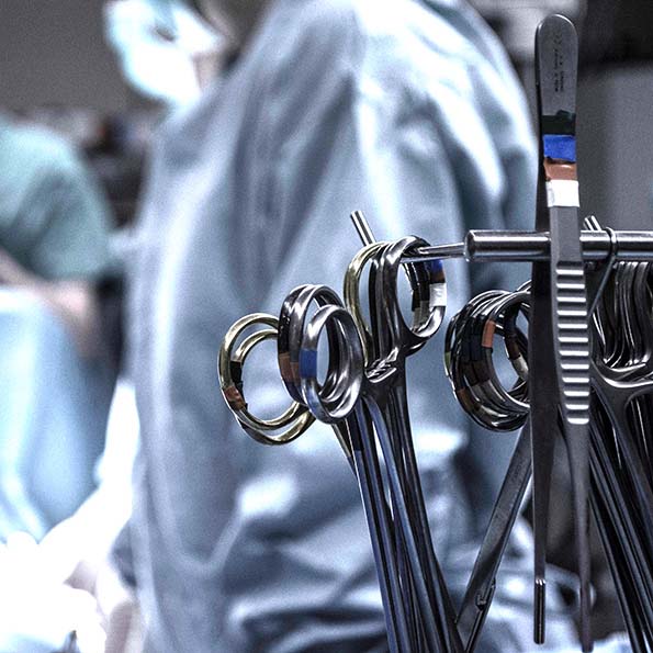 Close up of surgical equipment (scissors and tweezers) with surgeons in background