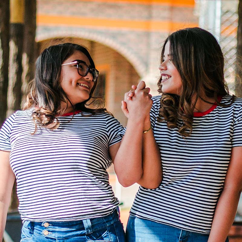 Two women holding hands and wearing the same stripped t-shirt