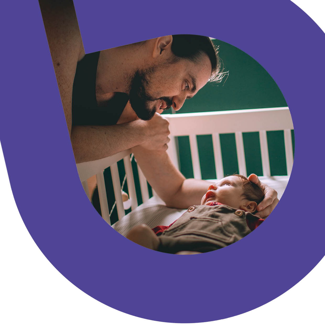 A father looking over his baby in a cot