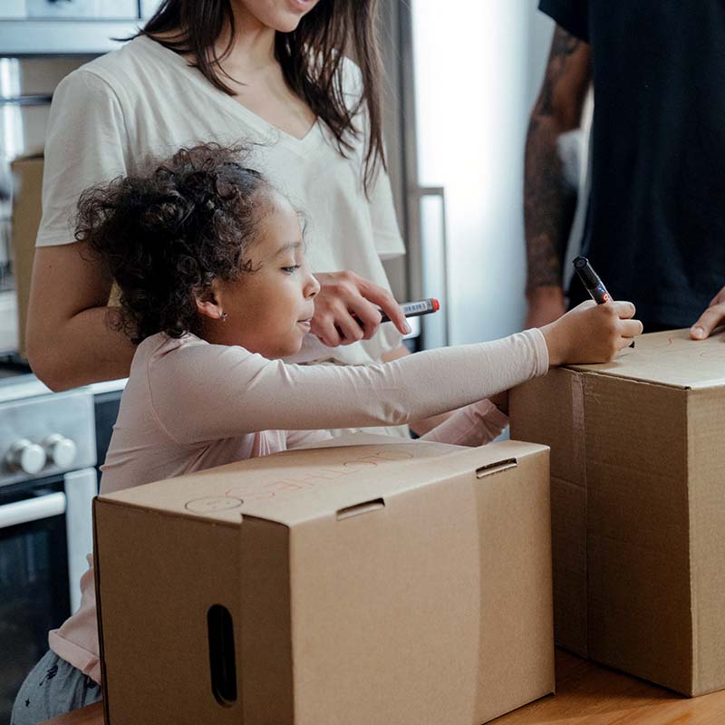 A little girl writing on packaging boxes