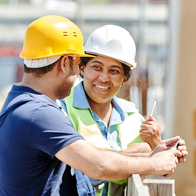 Woman and man in hard hats talking about home extensions