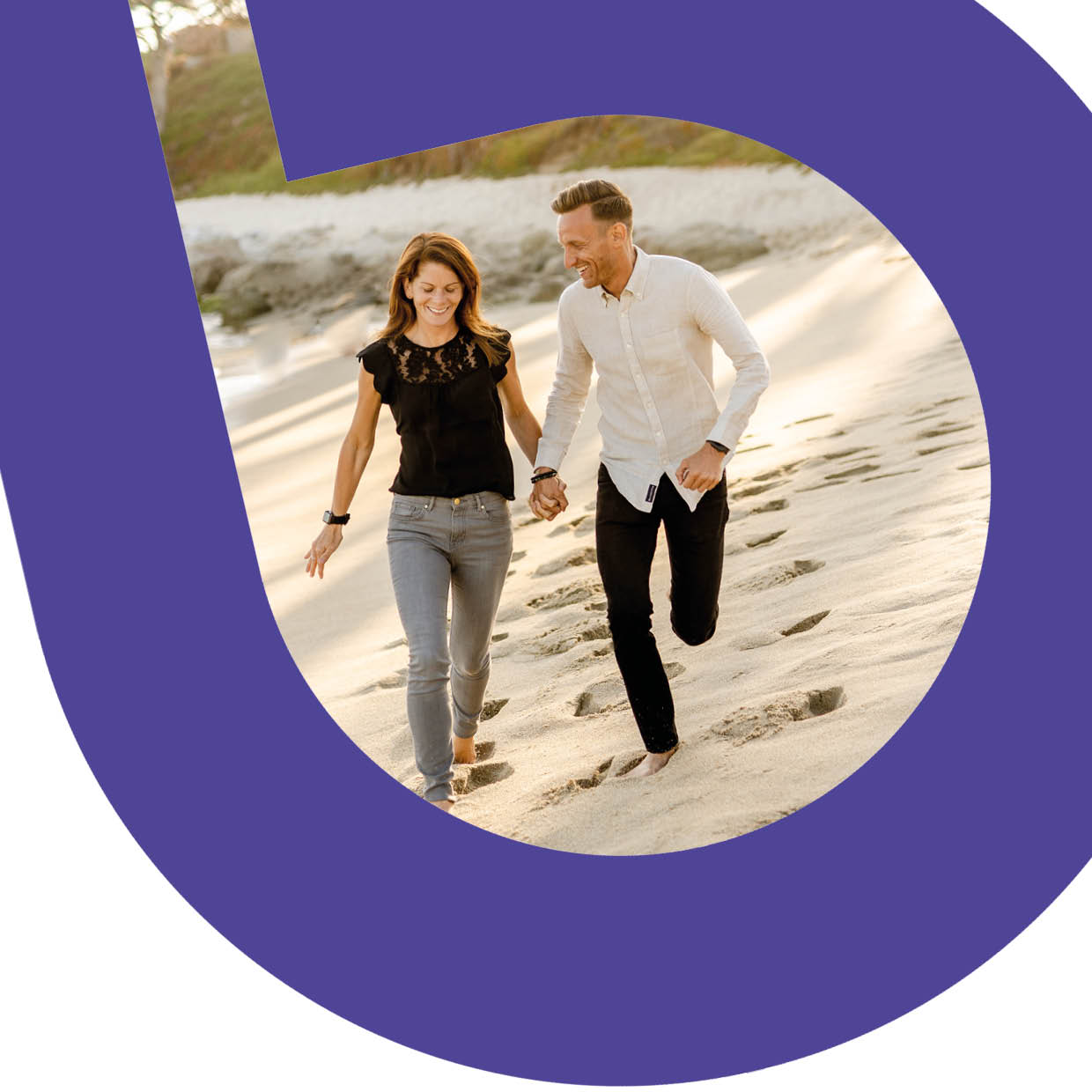 Man and woman walking along a sandy beach hand-in-hand