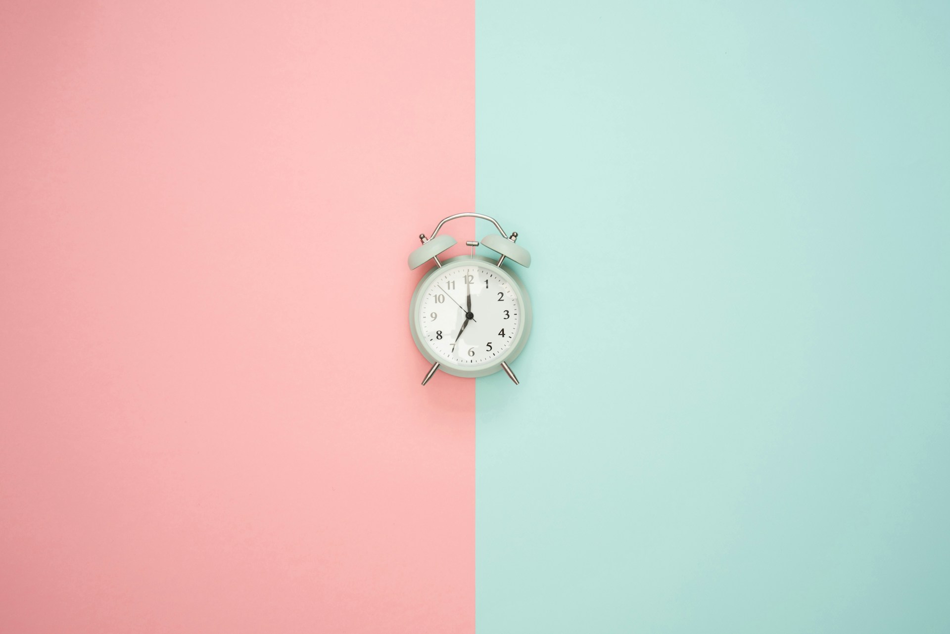 alarm clock on a split background of pink and green
